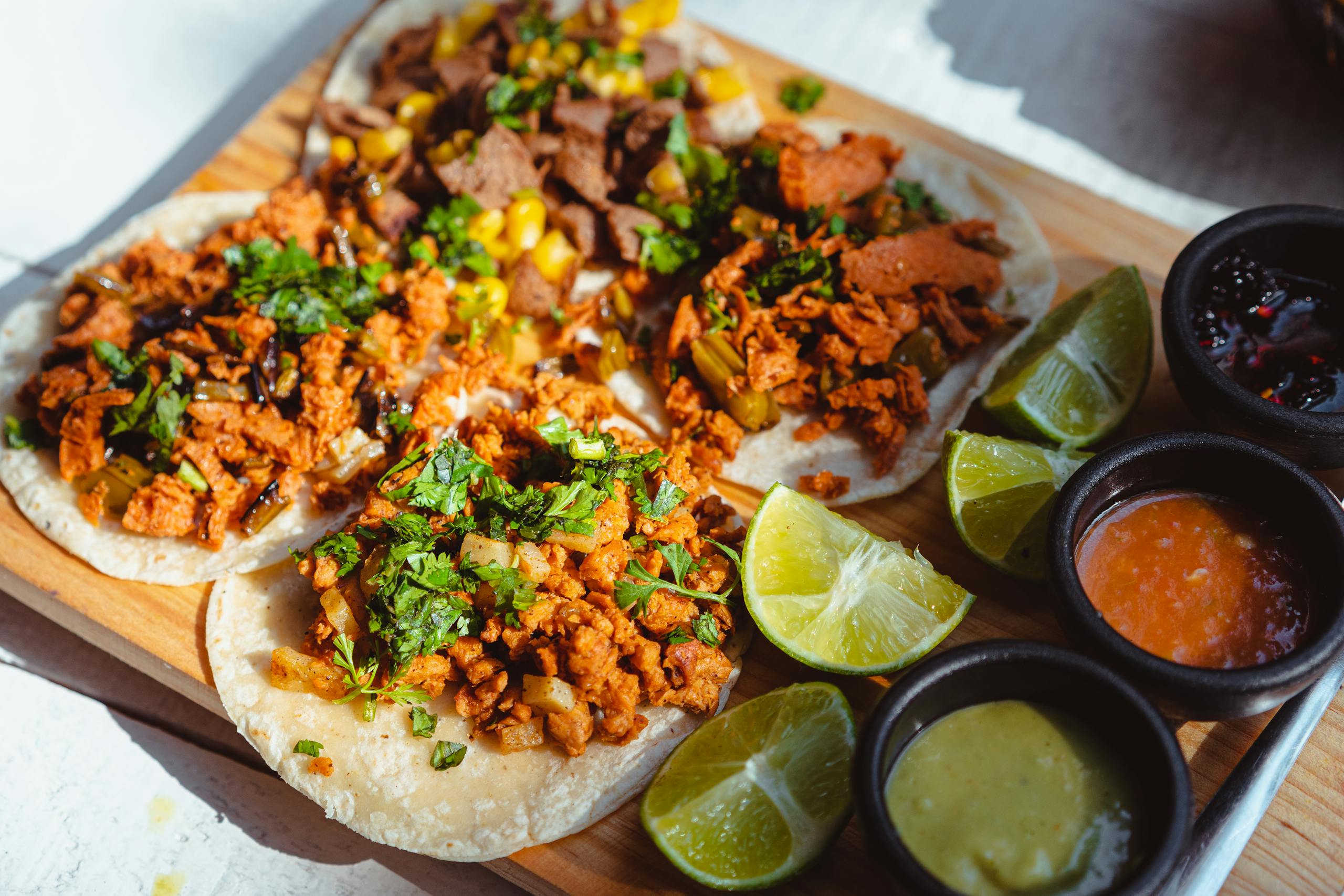 Close-up of savory tacos with fresh lime wedges and colorful sauces.